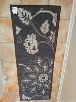 Top view of nylon carpet runner with dark gray background and large floral pattern in off-white and brown.