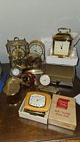 Overall group of various clocks showing different styles and brands including boxed Phinney-Walker clock and brass carriage clock.