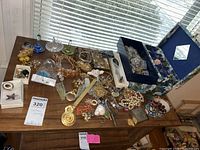 Wide view of table with three colored glass ring dishes, floral jewelry box and assorted jewelry spread
