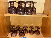 Six purple thumbprint stemware glasses arranged upside down on a top shelf showing the bowl design and base of glasses.