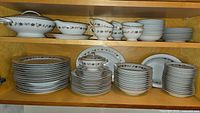 Full view of shelves containing the Noritake china pieces including plates, bowls, cups, saucers, and serving pieces.
