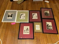 Seven framed prints laid on wooden floor, showing arrangement and framing details