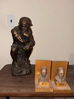 The Thinker sculpture and the carved wood bookends placed on a wooden surface against a wall.
