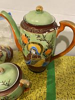 Photo of the tall handpainted tea/coffee pot with a lid showing traditional Japanese figure and floral designs