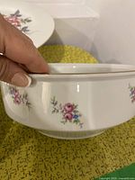 Close-up photo of an oval porcelain serving bowl showing floral decoration near the rim and gold trim.