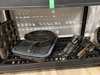 Photo showing a 12-cup muffin pan, cast iron fry pan, cast iron grill pan stacked and placed on a shelf.