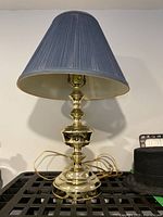 Full view of the brass traditional table lamp with blue pleated fabric shade showing the base and overall design