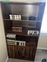 Front view of the brown laminate bookshelf with some books on the shelves and a small decorative box.
