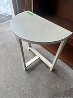 Image of white wood half-moon accent table from front angle showing legs and top design