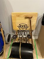 Metal art sculpture, cane, folding table, and black metal rack grouped together against wall on floor