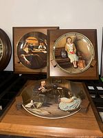 Three Norman Rockwell porcelain plates on wood mounts displayed, showing full artwork and frames.