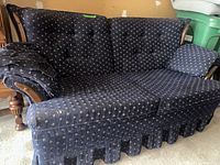 Photo showing the loveseat from a side angle to highlight the wooden armrests and overall fabric pattern and condition.