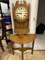 Photo showing the half-moon wooden table and the Caravelle wooden wall clock mounted together, displaying the full table and clock shape and details.