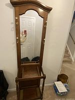 Full view of traditional wood hall tree showing mirror, hooks, and lower shelf