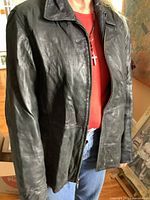 Front view of the black leather Anne Klein coat worn by a person showing the front zipper closure and collar detail.