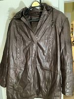 Front view of brown leather coat showing zipper and snap button closure, two zippered pockets and side pockets.