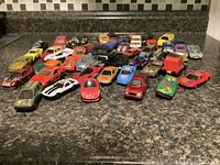 Front angled view of 30+ diecast toy cars arranged in rows showing various colors and models.