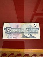 Front side of older Canadian five dollar bill featuring portrait and denomination.