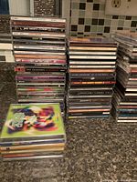 Multiple stacks of music CDs in jewel cases, showing titles and cover art variation