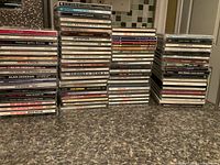 Photo of multiple stacks of music CDs, showing various artists and album titles