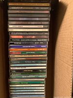 Stack of various music CDs showing artist and album names on spines.