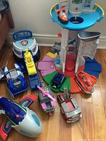 Full view of Paw Patrol Lookout Tower and eight Paw Patrol character vehicles arranged on floor.