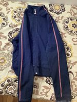 Navy blue jacket laid flat showing full front with pink stripes on sleeves