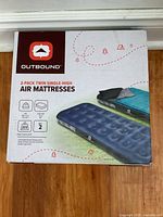 Photo of the front of the box showing the Outbound brand, product name as 2-pack twin single-high air mattresses, and image of two navy blue mattresses with camping background.