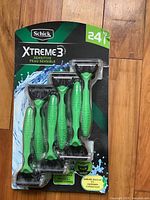 Front view of Schick Xtreme3 Sensitive disposable razors pack containing 24 razors with green handles.