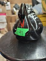 Front view of the black ceramic swan figurine showing facial details and orange beak