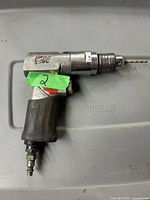 Front angle view of Campbell Hausfeld pneumatic air drill showing the rubber grip and reversible chuck with drill bit installed.