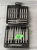 Photo of a black plastic case opened, displaying 20 precision driver bits and 4 bit extension bars arranged in molded slots.