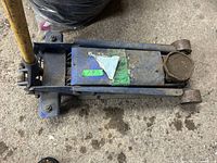 Top view of hydraulic floor jack showing yellow handle, blue body, and lifting pad