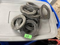 Photo of eight black rubber washers stacked on a plastic tub lid with a green label showing number 48.