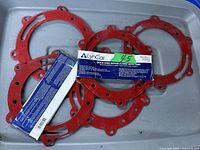 Five red quick ring repair flanges with tabs laid out on a gray surface alongside packaging with Lyn Car branding and product label.