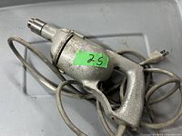 Side view of silver electric drill with power cord and plug showing general condition and cord length.