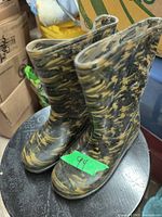 Pair of rubber boots in black and tan camouflage pattern standing on a stool.