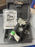 Photo of Surebonder 6600A pneumatic air stapler inside a black plastic carrying case with user manual visible.