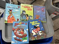 Photo showing five vintage Disney children's books: The Brave Little Tailor, The Jungle Book, Winnie the Pooh and the Honey Tree, DuckTales: Subterfuge on the Sea, Gulliver Mickey.