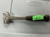 Side view of the full tool showing wooden handle with green label and metal end stamped 'PM-132 WHEEL WEIGHT TOOL'