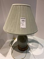Full view of the ceramic lamp with pleated fabric shade showing overall shape and size.