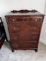 Front view of the four drawer wooden dresser showing the dark wood finish and brass handles