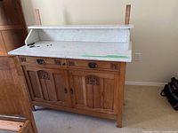Full front view of oak dresser with white marble top, marble shelf supports, two drawers and cabinet below