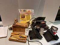 Full view of the lot with Craftsman belt sander, wooden box with carving tools, leather pouch, and a packet of 3M sandpaper.