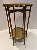 Full view of the two-tier vintage plant stand showing wooden legs and brass trays.