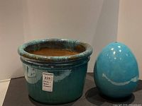 Photo showing the round garden planter and egg-shaped garden ornament next to each other, both in turquoise ceramic with glossy finish.