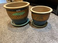Front-facing photo of two ceramic pots with attached trays, showing their exterior and decorative patterning