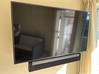 Front view of Samsung TV mounted on stand with Sonos Playbar beneath