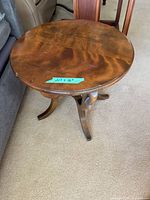 Angled view of the round wood side table showing three-legged pedestal base and wood grain surface with measurements sticker (21" x 18")