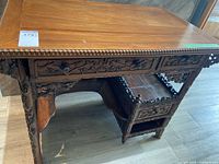 Three-quarter view of carved wooden writing desk showing overall shape and design
